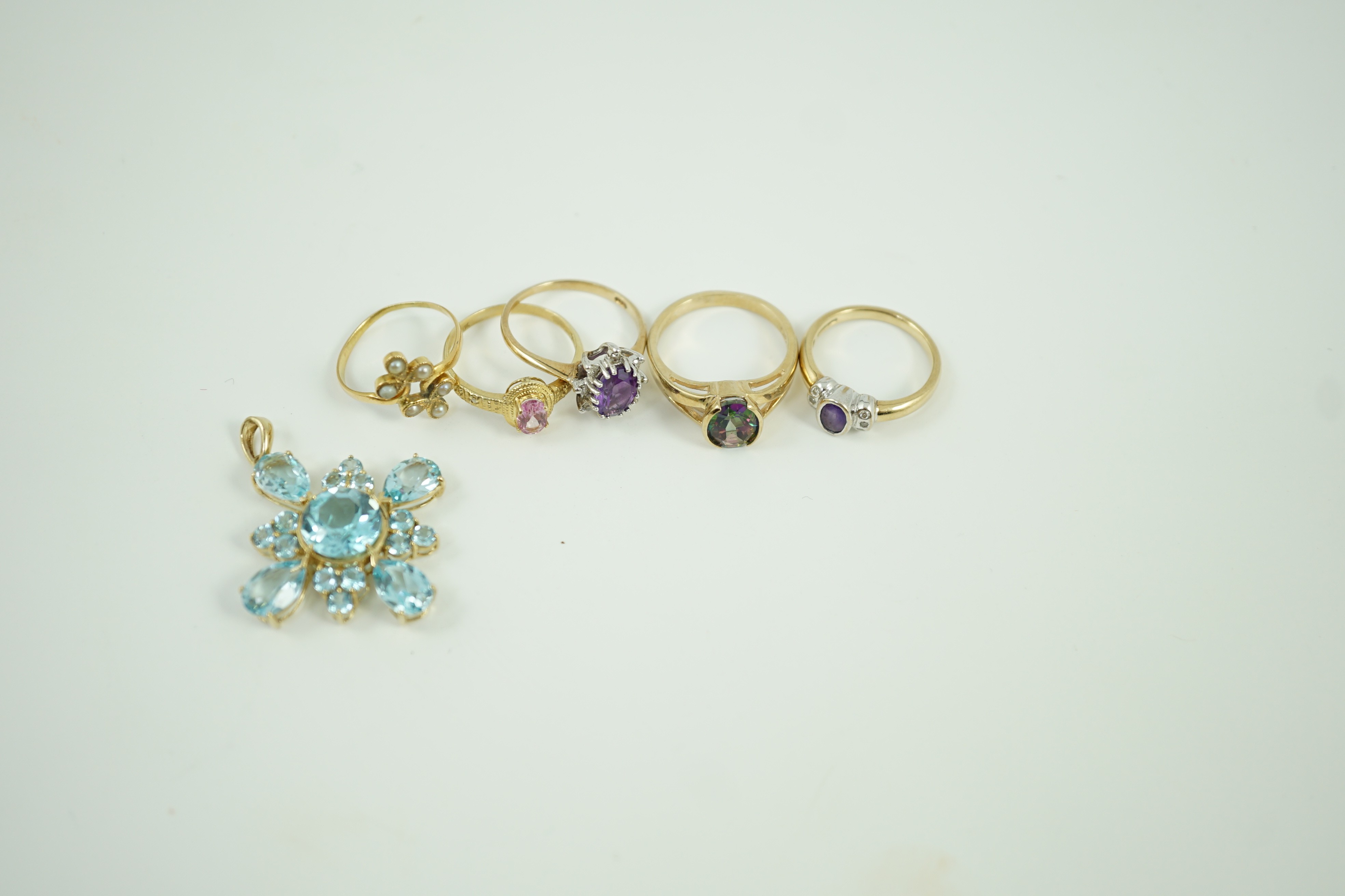 Four assorted modern 9ct gold and gem set rings, a white metal and seed pearl ring and a 9ct gold and blue stone cluster set pendant, 33mm, gross weight 17.9 grams.